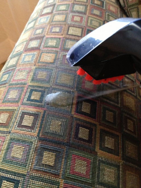 Using the hose attachment of the BISSELL ProHeat 2X Upright Deep Carpet Cleaner to clean furniture.