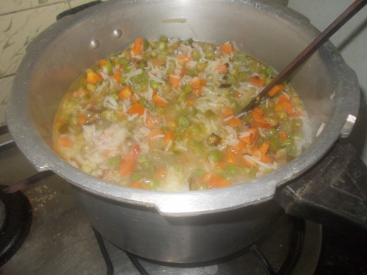 Transfer the vegetable into half cooked rice.