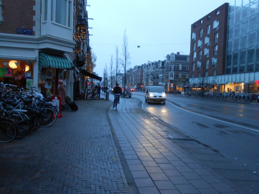 A brick sidewalk to the left for pedestrians, a bike lane, and the main street to the right.
