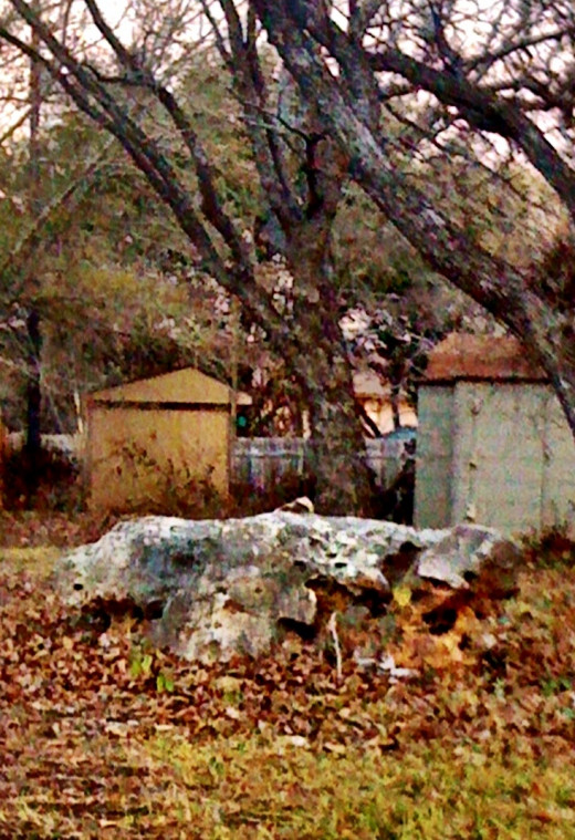 Large stone on a large lawn covered with trees.