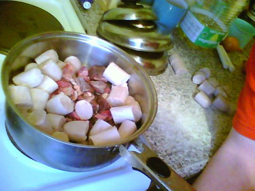 The diced beef, beef sausages and onion in the pan before adding the beef stock