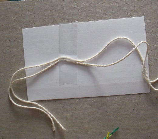 Tape two strands of cotton kitchen string to a 3x5 card or to cardboard for stability.
