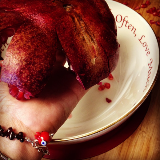 Using your non-dominant hand, hold the pomegranate seed-side down in your palm over the bowl.  