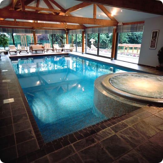 Modern Indoor Swimming Pool with Round Hot Tub with natural wood beams, stone floor and sliding doors