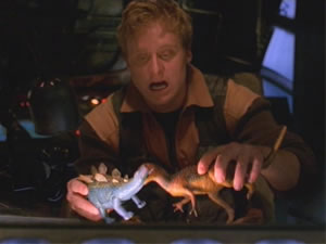 Wash, the ship's pilot playing with his dinosaurs while the others are on a salvage mission.