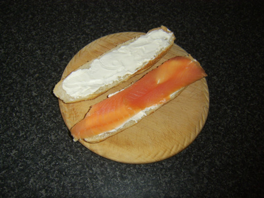 Smoked salmon is laid on bottom half of sub roll