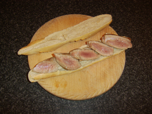 Tuna slices are laid on bottom half of baguette