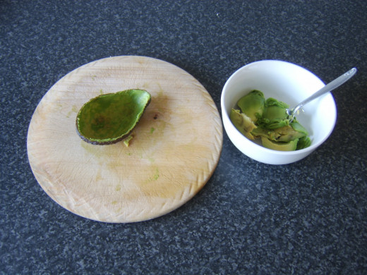 Flesh is scooped out of avocado half with a teaspoon