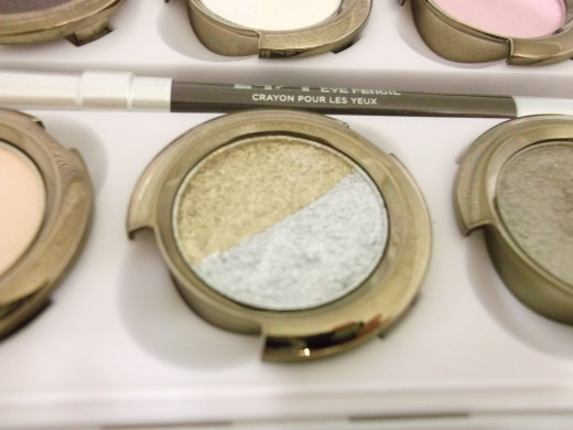 Closeup of Oz eye shadow. There are two separate shadows in this pan. One is glittery gold and the other is glittery grey.