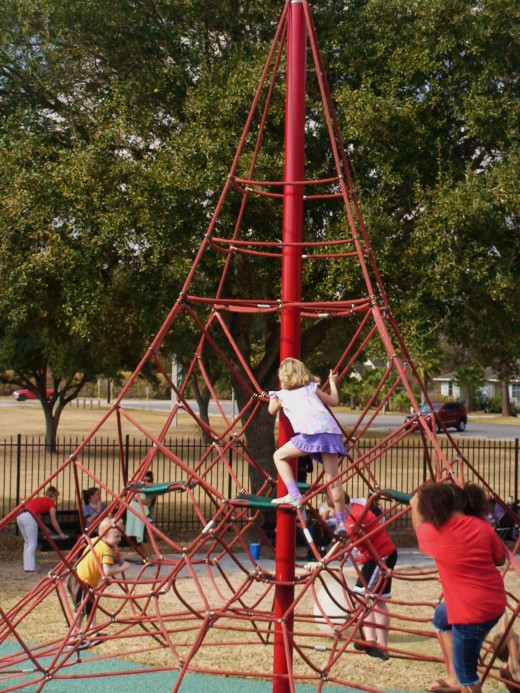 The children climb TOWARD the top of the playground equipment.