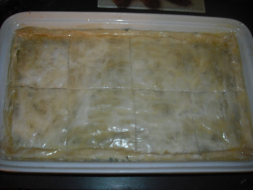Roll down the sides of the dough, brush with butter, and score the top layer of phyllo into serving sized portions.