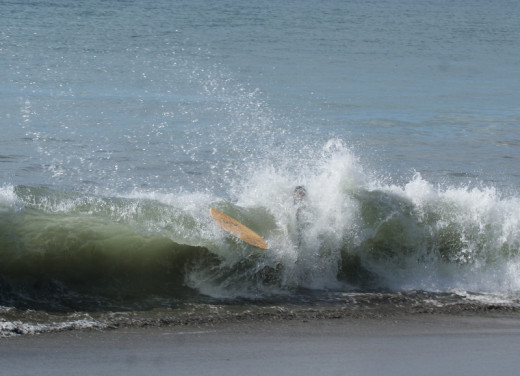 Skim boarding in the surf breaking on the beach on Playa Hermosa one day where there were strong waves.