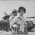 A Korean girl carries her brother past a stalled U.S. tank near Haengju, Korea, June 1951