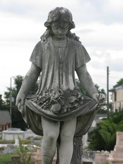 A young girl uses her skirt to carry flowers to the grave of 7 year old "Carrie W." in the Hecker plot. 