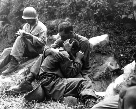 Msgt Frank Chandler, US Army 5th Regimental Combat Team, comforts a soldier who had just identified his best friend's body.