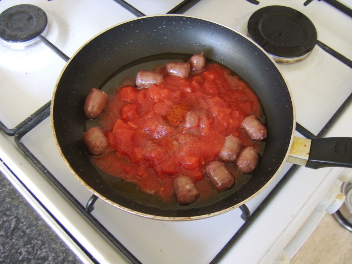 Tomatoes and spices are added to browned sausage pieces