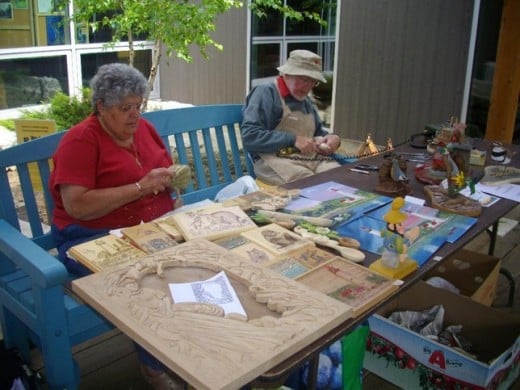 First Nation and Mennonite representatives at a booth at Visitor Centre carving products out of wood.