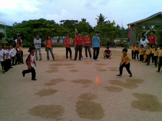 Children being taught how to play the game "Dog and Bone"