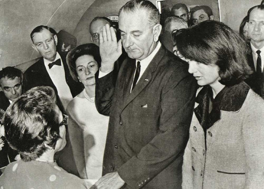 President Johnson being sworn in on Air Force One with Mrs. Kennedy still wearing suit smeared with President Kennedy's blood