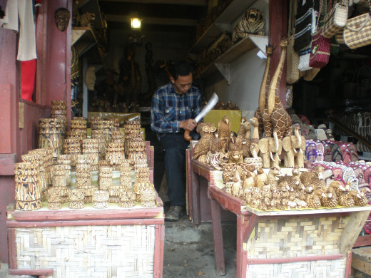 A man works on a craft and sell the product at his shop.