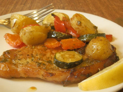 pork chop and roasted vegetables on plate, with slice of lemon to garnish