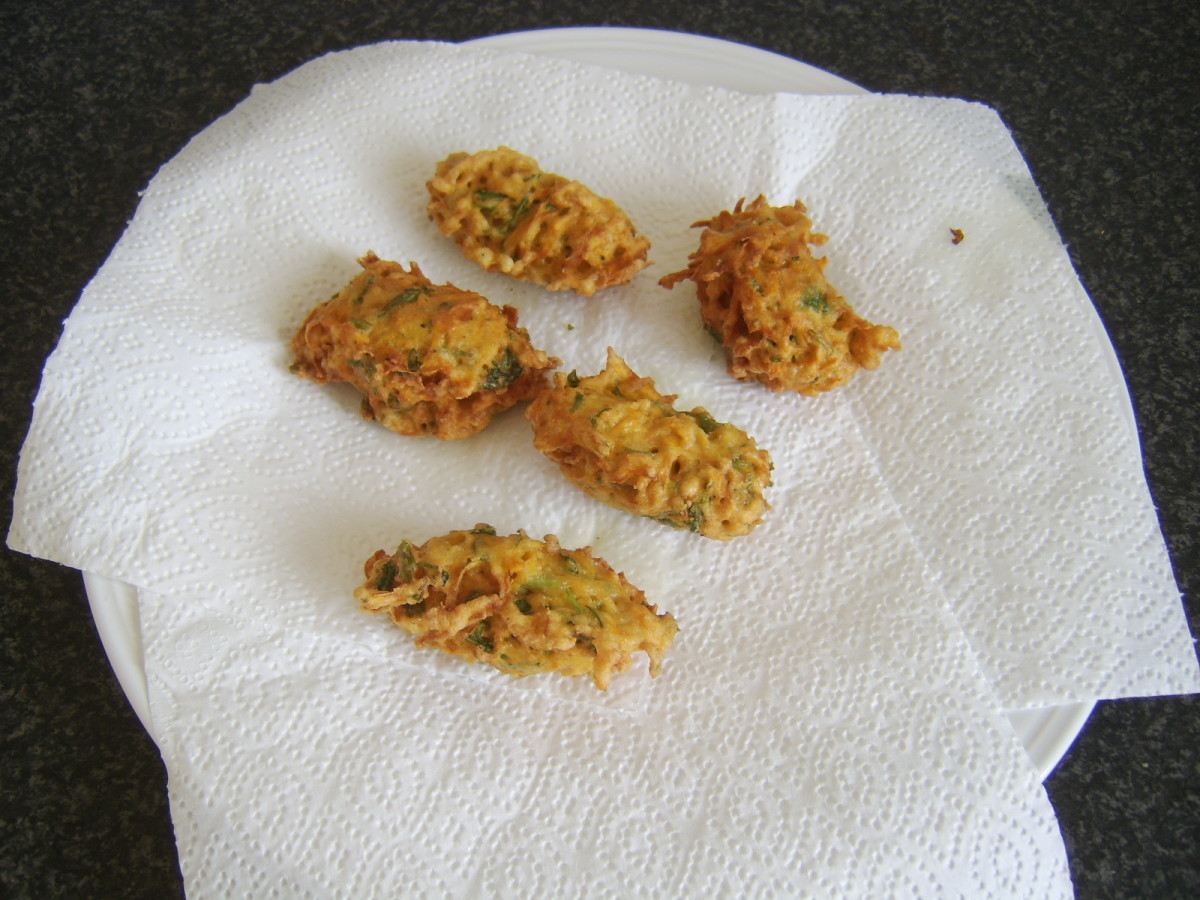 Deep fried sweet potato fritters are drained on kitchen paper