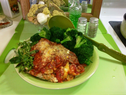 Image of family-style serving of the tomato, sweet basil, and Parmesan chicken dish with steamed broccoli florets. Chicken tenders were cooked in a light spice breading before pouring parmesan sauce over all.