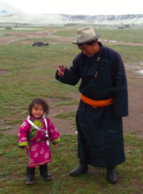 A nomad father and child weathering an early season blizzard at Orkhon waterfall