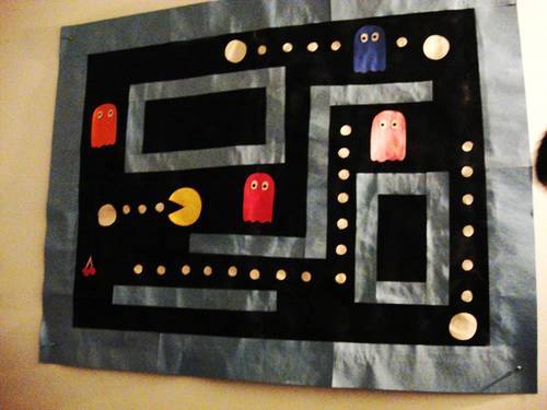 an example of a poster made by me of a pacman scene. made from wrapping paper, spray paint, and construction paper. over 4 feet in width. 