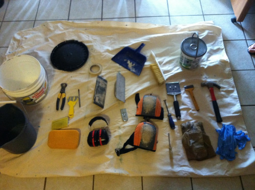 Tile working tools and gear laid out on a drop cloth.