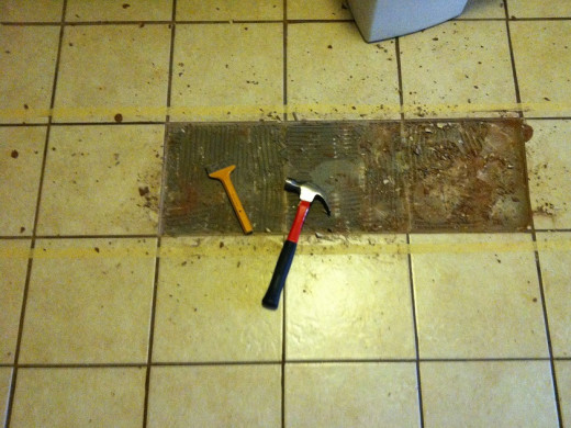 Busting out the tile with a mason's chisel and a hammer.