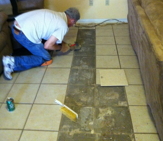 Chipping away the grout on the sides to make room for the new tile.