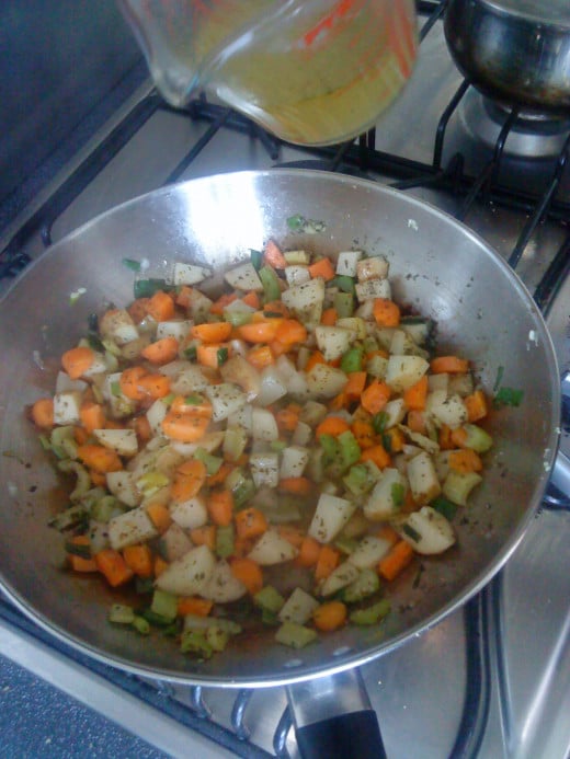 Adding stock to vegetable mix.