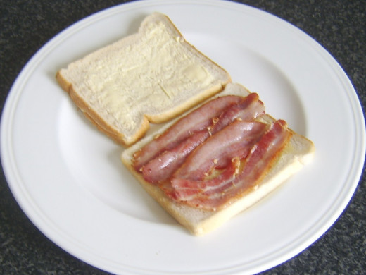 Bacon is laid on buttered slice of bread