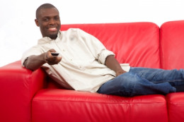 A guy sitting on a couch with a remote control A guy sitting on a couch with a remote control