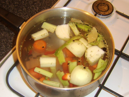 Vegetable stock ingredients are put on the heat to reach a simmer
