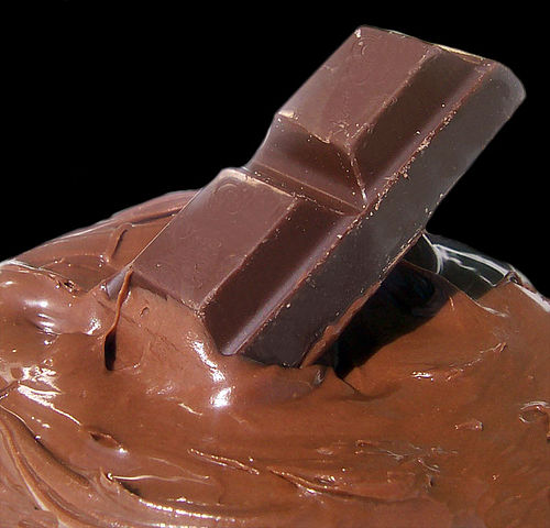 A piece of chocolate bar dipped in molten chocolate