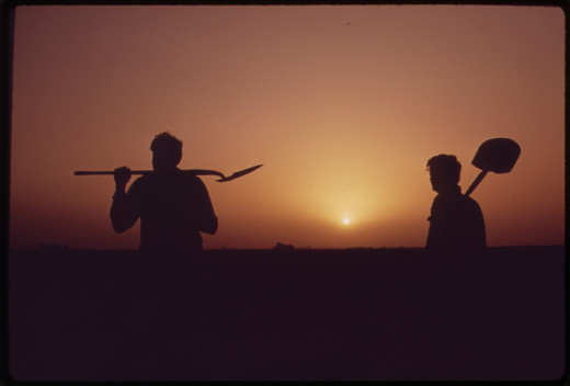 FARM WORKERS SHOULDER TOOLS AT END OF DAY