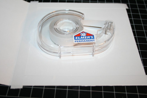 This is double-sided tape by Elmers.  They do sell a product called Scor-Tape which is essentially double-sided tape with a peel-off strip.  