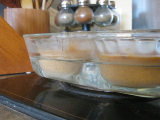 Here is the pumpkin mix spooned evenly into custard dishes with the appropriate amount of boiling water poured into the surrounding baking dish.