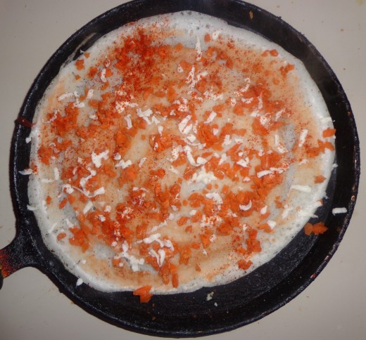 Sprinkle red chilly powder and salt evenly on the cooking dosa