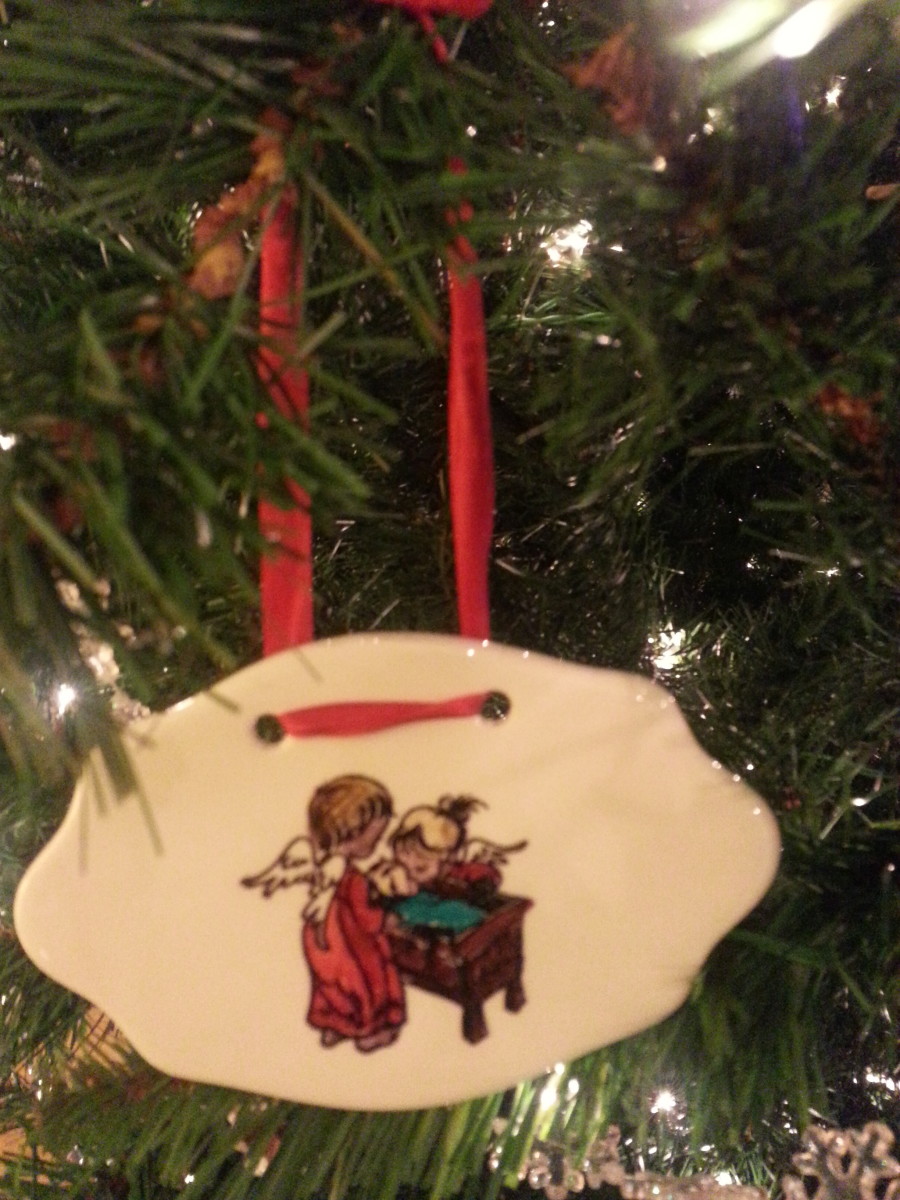 Hand stamped ceramic ornament given by another family member.  Two angels (sisters) watching over little brother in cradle. 