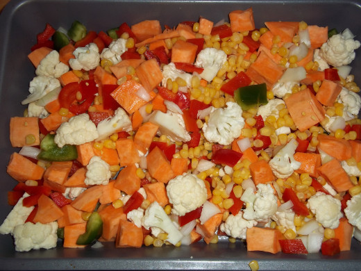 Vegetables going in the oven to roast, drizzled with olive oil, cumin, and garlic powder. 