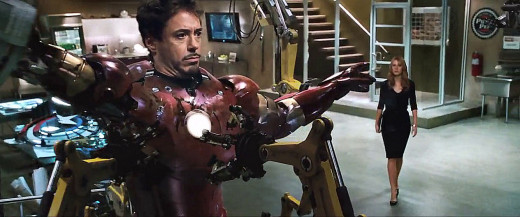 As Gorgeous-Girl Gweneth approaches... This is the "famous" scene "Hinting" at the MARVEL comix, inter-relationships.  Here, you see Capt. America's "SHIELD" under construction in Tony's shop. "Are those BULLET-Holes !" She is, of course, SHOCKED... 