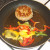 Bell peppers are added to pan with partly fried pork burger