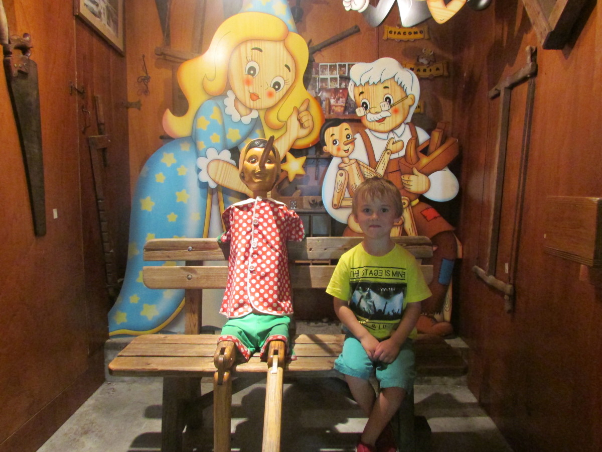 Our son, sitting next to the wooden puppet outside the 'Pinocchio' shop.