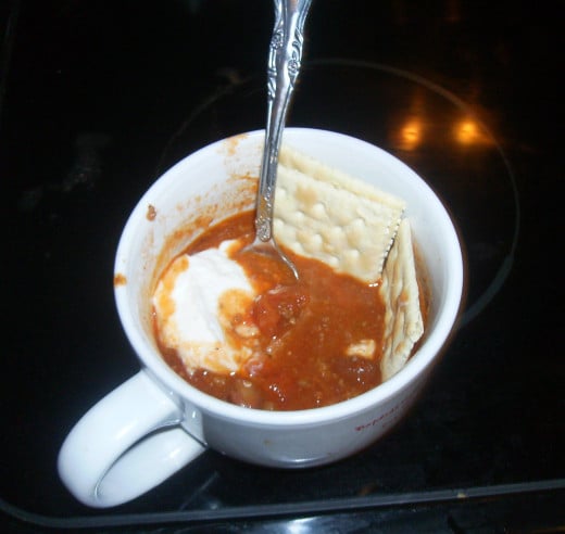 Cup of homemade chili with crackers and sour cream