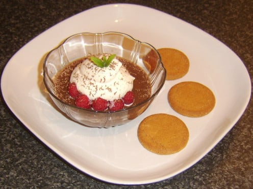 Raspberry and cream dessert is plated with ginger biscuits