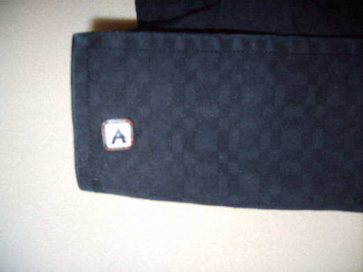 A monogrammed cufflink stands out on this black shirt