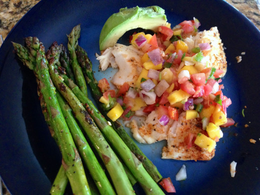 Tilapia topped with mango salsa with a side of avocado and grilled asparagus